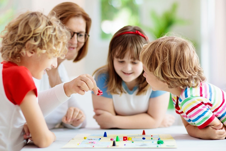 Family playing board game at home. Kids play strategic game. Little boy throwing dice. Fun indoor activity for summer vacation. Siblings bond. Educational toys. Friends enjoy game night.