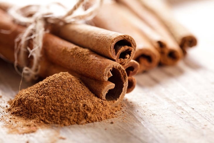 Cinnamon sticks and meal close up on wooden table