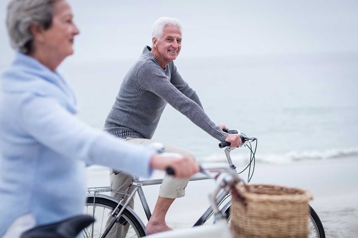 Senior couple having ride with their bike on the beach